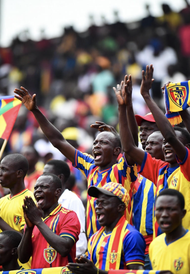 Hearts of Oak fans chanting at Accra Sports Stadium, waving red and yellow scarves